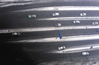 车辆行驶在郑州市的道路上。河南省气象台发布道路结冰黄色预警信号，雪雨天气影响返程并不利于城市早高峰交通。新华社发