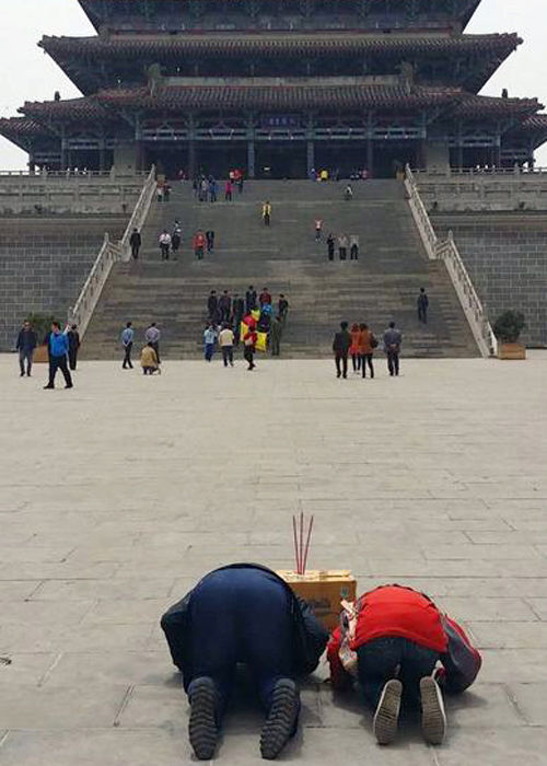 男子在烧香跪拜求升官。