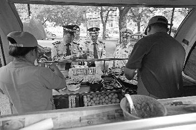 在西直门内大街一早餐车点，执法人员在检查早餐车证件