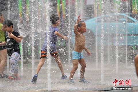 7月20日，北京天气炎热，孩子们在喷泉中嬉水纳凉。