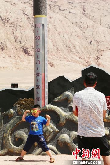 小小男子汉在62度温度计下拍照。　艾西丁？托乎提 摄