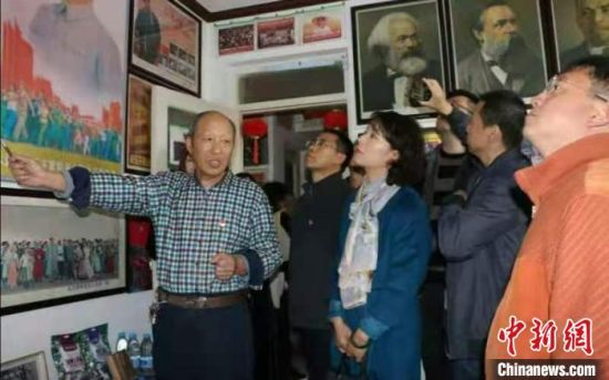 现居住于甘肃省嘉峪关市的古稀老人张天顺在不到60平方米的家里，布置起了爱国主义教育基地。图为张天顺(左一)向参观者进行讲解。(资料图)受访人供图