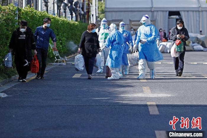 康复者带着自己的行李，在医护人员的陪伴下走出方舱医院。　殷立勤 摄
