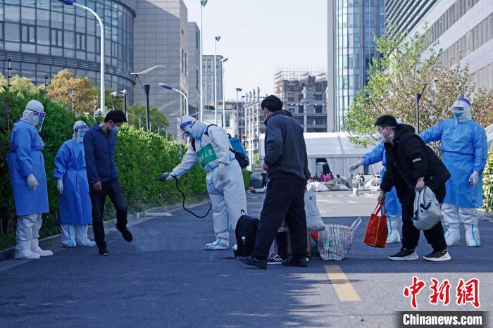 康复者带着自己的行李，在医护人员的陪伴下走出方舱医院并消毒。　殷立勤 摄
