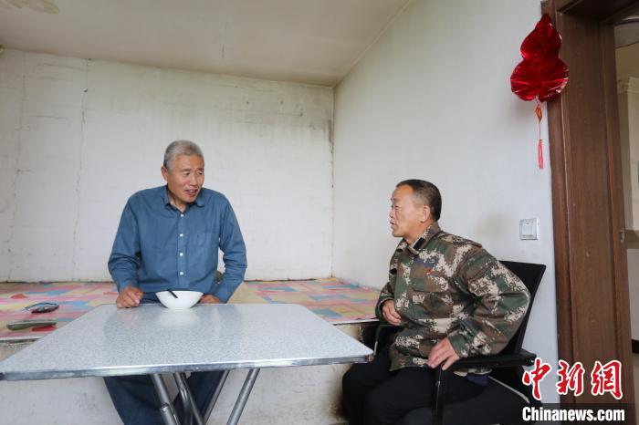 图为瞭望员王正军(左)上塔前与郑洪山交流。　何康红 摄