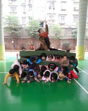 数名幼儿夹垫子中老师坐上方 园方:锻炼抗压能力