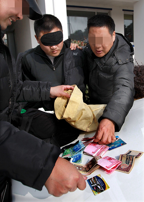 反扒队员在搜查扒窃嫌疑人（戴眼罩者）携带的背包（1月19日摄）。新华社记者 凡军 摄