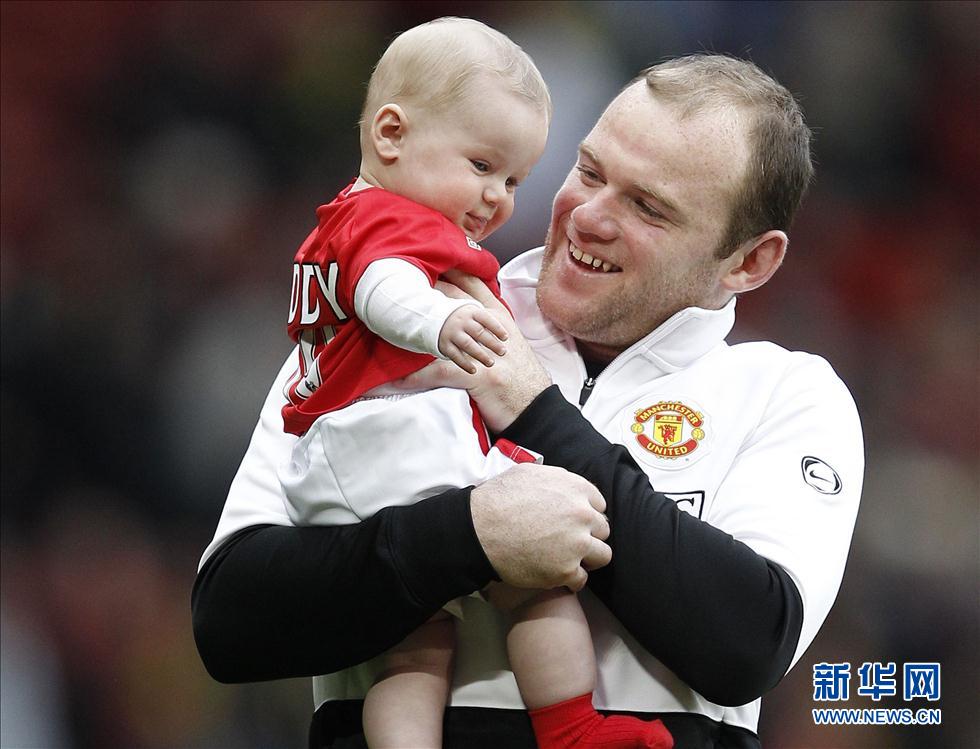 图为2010年5月9日，英格兰球员鲁尼在英超一场比赛后怀抱自己的儿子凯·鲁尼。 新华社/路透