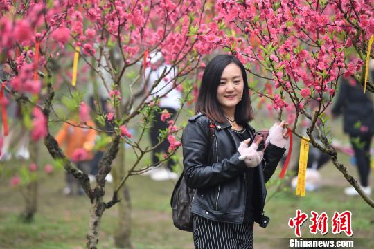 图为民众在桃花树丛中拍照留念。　俞靖 摄