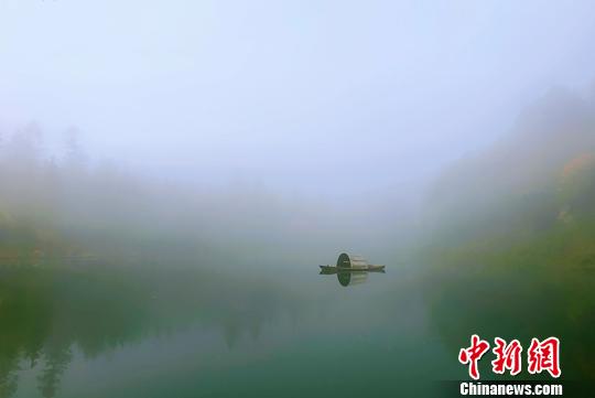 一叶扁舟泛于湖上，树木与水中倒影相映成趣。　赵鹏　摄